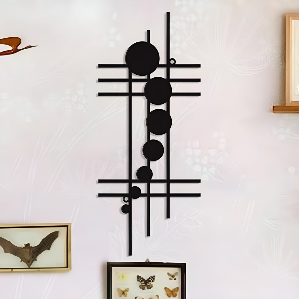 Black geometric iron wall decor with lines and circles displayed on a light wall with framed butterfly art