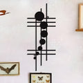 Black geometric iron wall decor with lines and circles displayed on a light wall with framed butterfly art