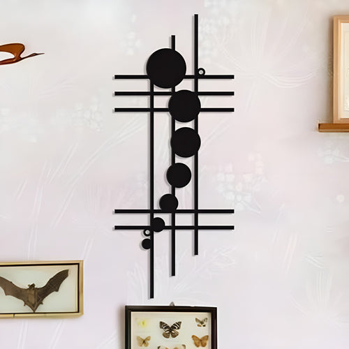 Black geometric iron wall decor with lines and circles displayed on a light wall with framed butterfly art