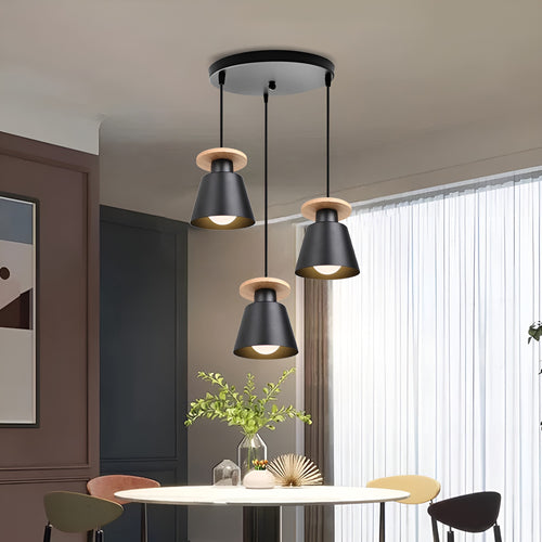 Black iron three-head pendant light with wood accents hanging above a dining table