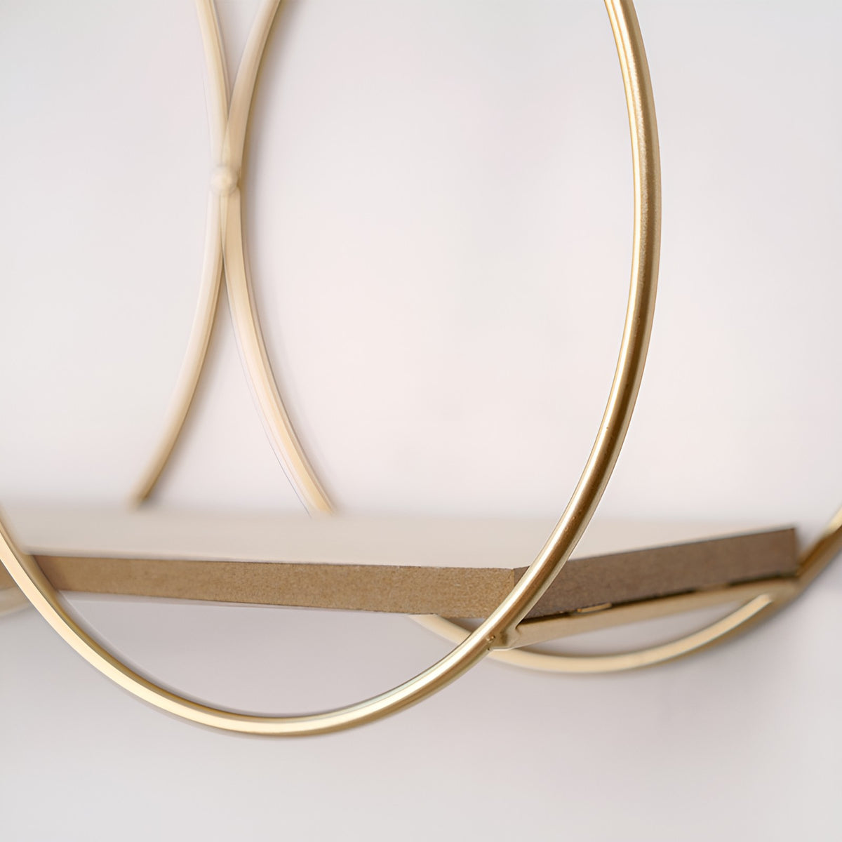 Close-up of a gold round iron wall shelf frame with a wood shelf on a white wall